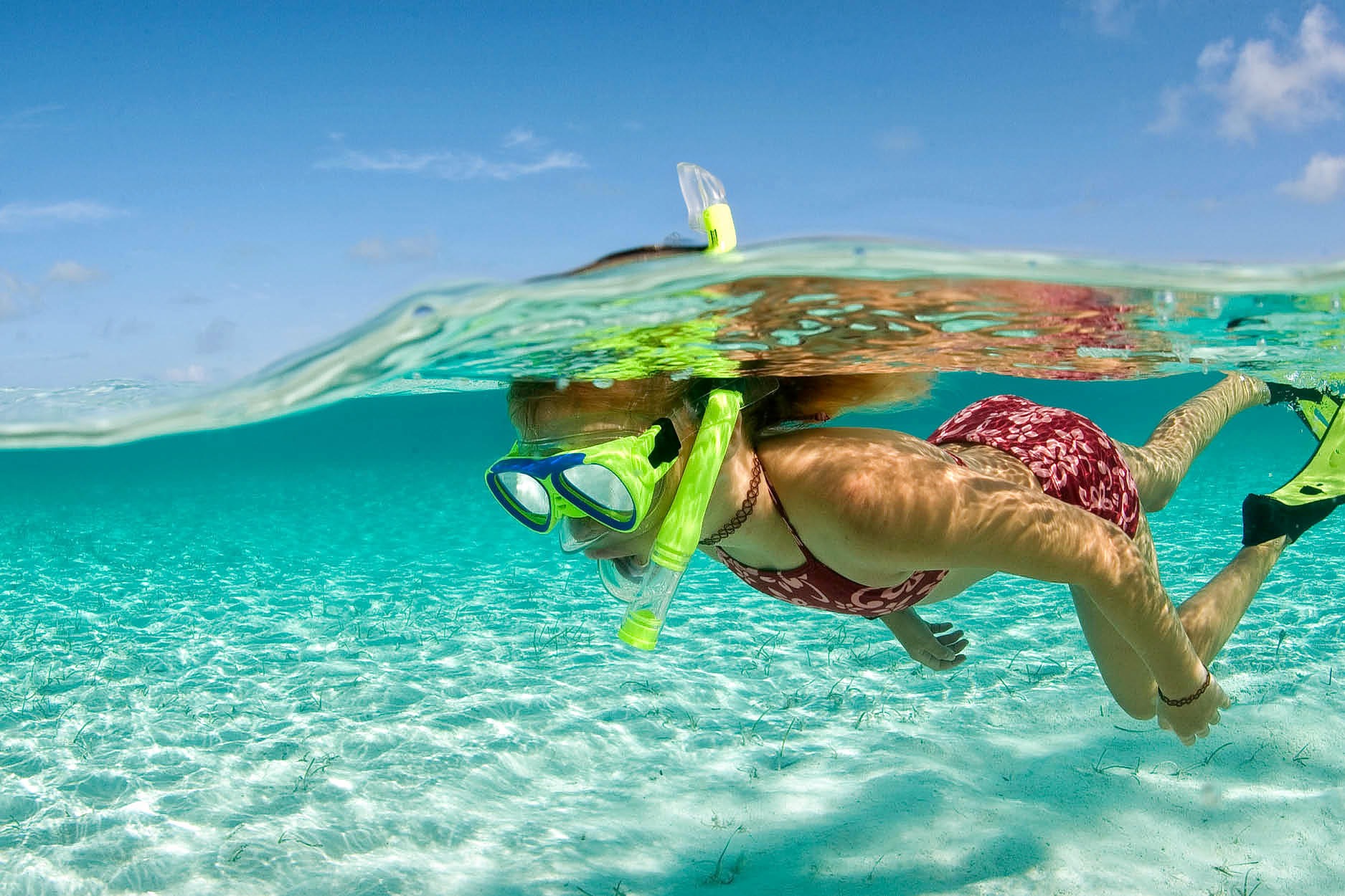 A snorkeler at the surface in clear turquoise water, half above and half below the waterline
